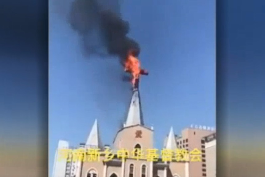 A still from a video shows a cross at the top of a church on fire.