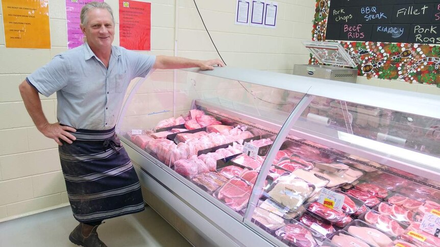 Butcher stands in front of a meat display in a butcher shop