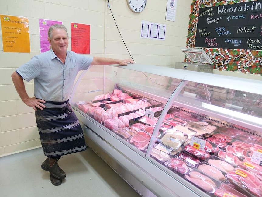 Butcher stands in front of a meat display in a butcher shop