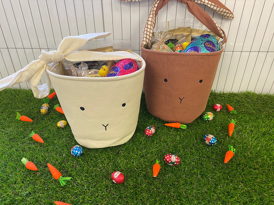 Two Easter bunny baskets with Easter eggs on artificial turf.