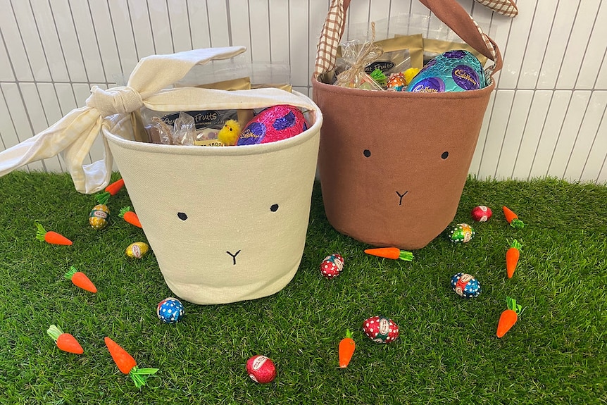 Two Easter bunny baskets with Easter eggs on artificial turf.