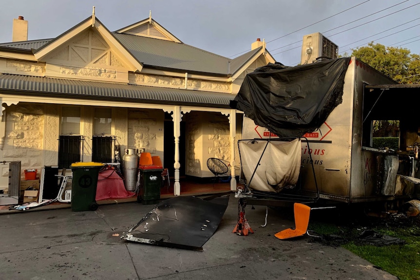 The burned remains of a food van in a front garden.