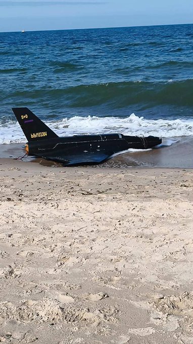 A profile image of a black and white drone sat on a beach.