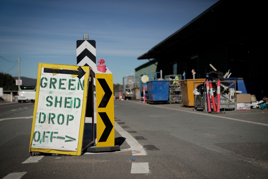 A sign on the road next to a recycling depot that reads 'Green Shed Drop Off' with an arrow.