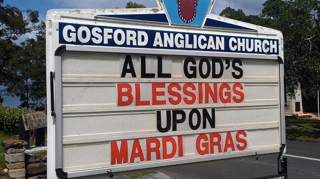 A sign reads, "All God's blessings upon Mardi Gras."
