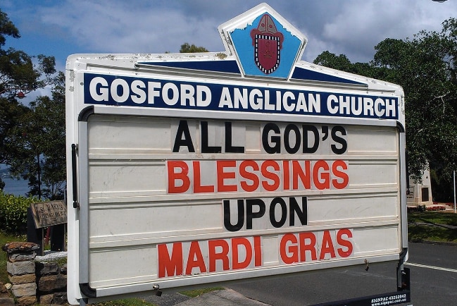 A sign reads, "All God's blessings upon Mardi Gras."