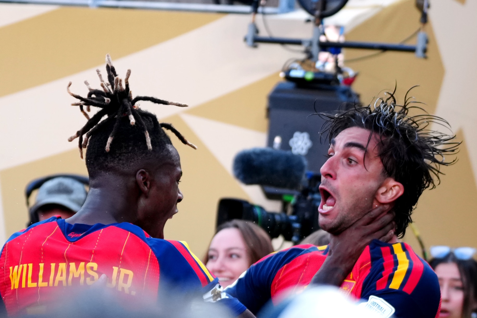 Two excited male soccer players, one with his hand on the neck of the other.