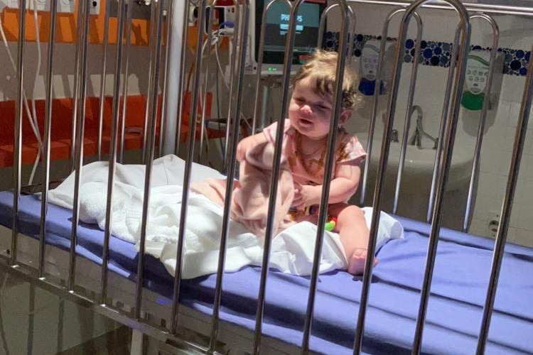Toddler sitting up in hospital cot