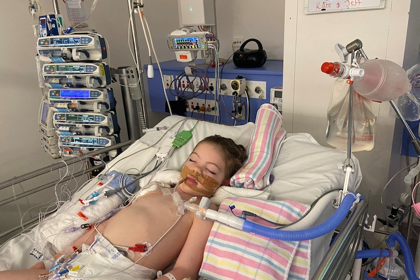 Young girl sleeping in hospital bed being monitored by machines