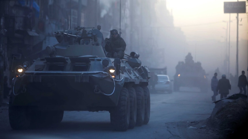 Russian soldiers ride on armoured vehicles through a street in Aleppo, Syria.