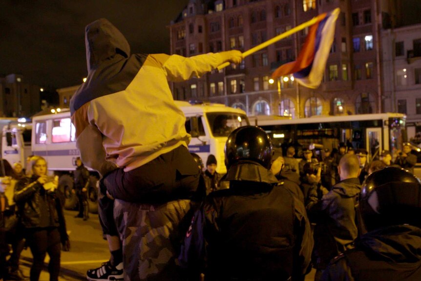 Man waving Russia flag surrounded by police