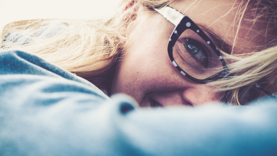 A blonde woman in designer glasses smiles.