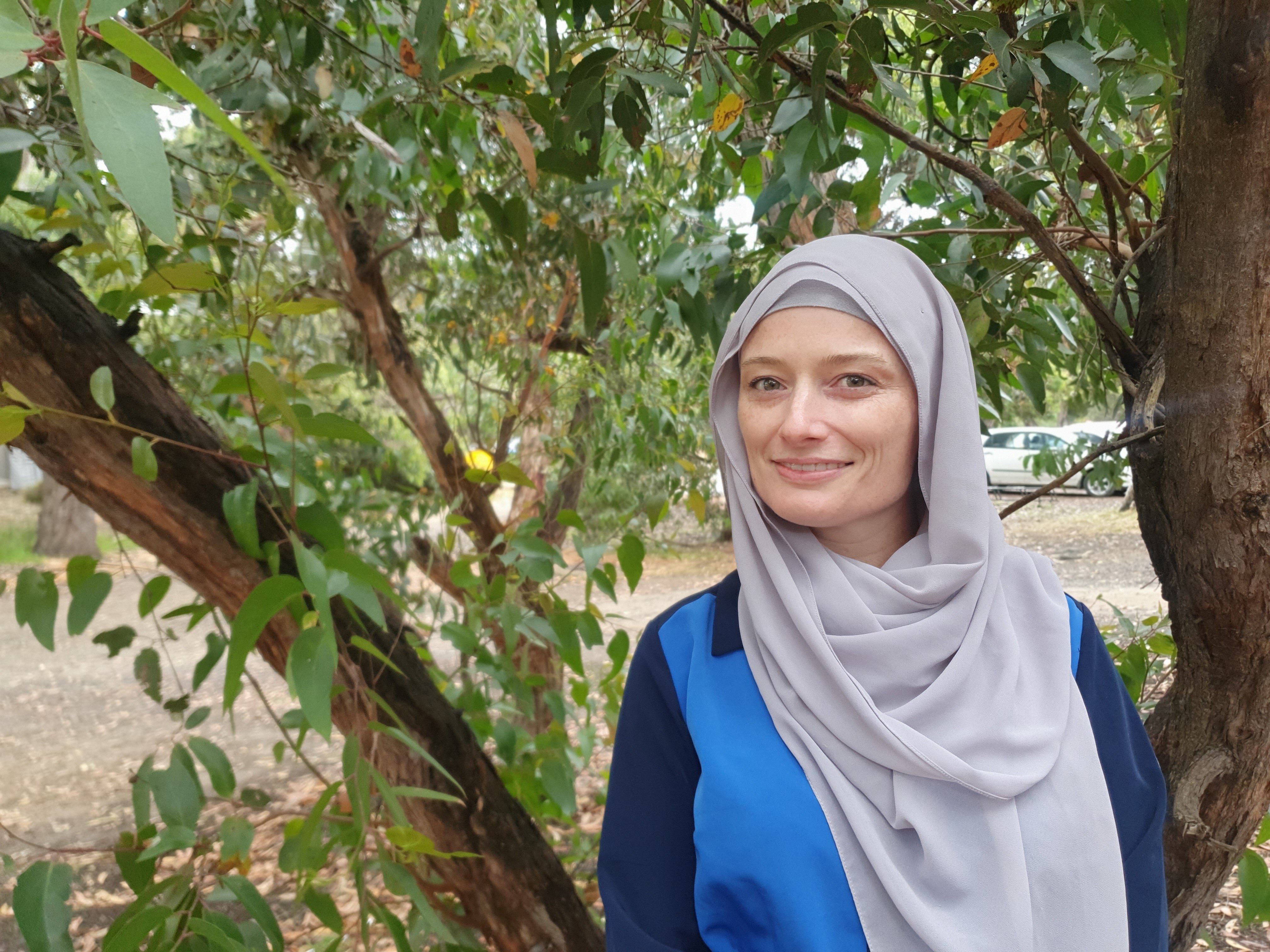 A woman wearing a headscarf standing in front of a tree