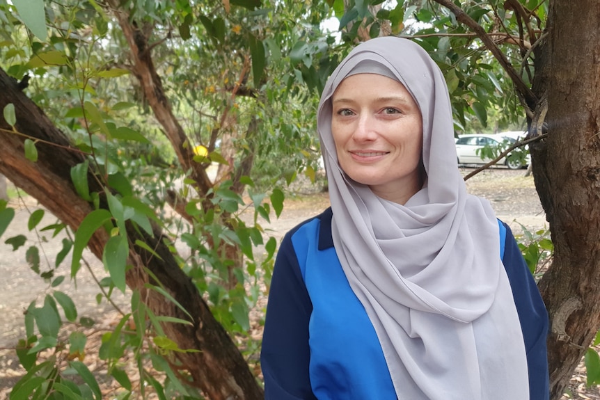 A woman wearing a headscarf standing in front of a tree