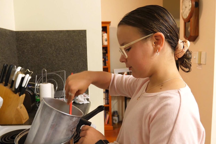 young girl in the kitchen with pots and pans stirring something