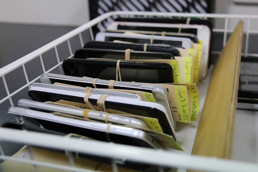 A line up of mobile phones in a basket