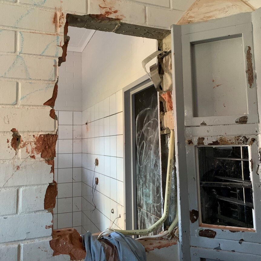 A chunk of wall is missing from a prison cell