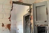 A chunk of wall is missing from a prison cell