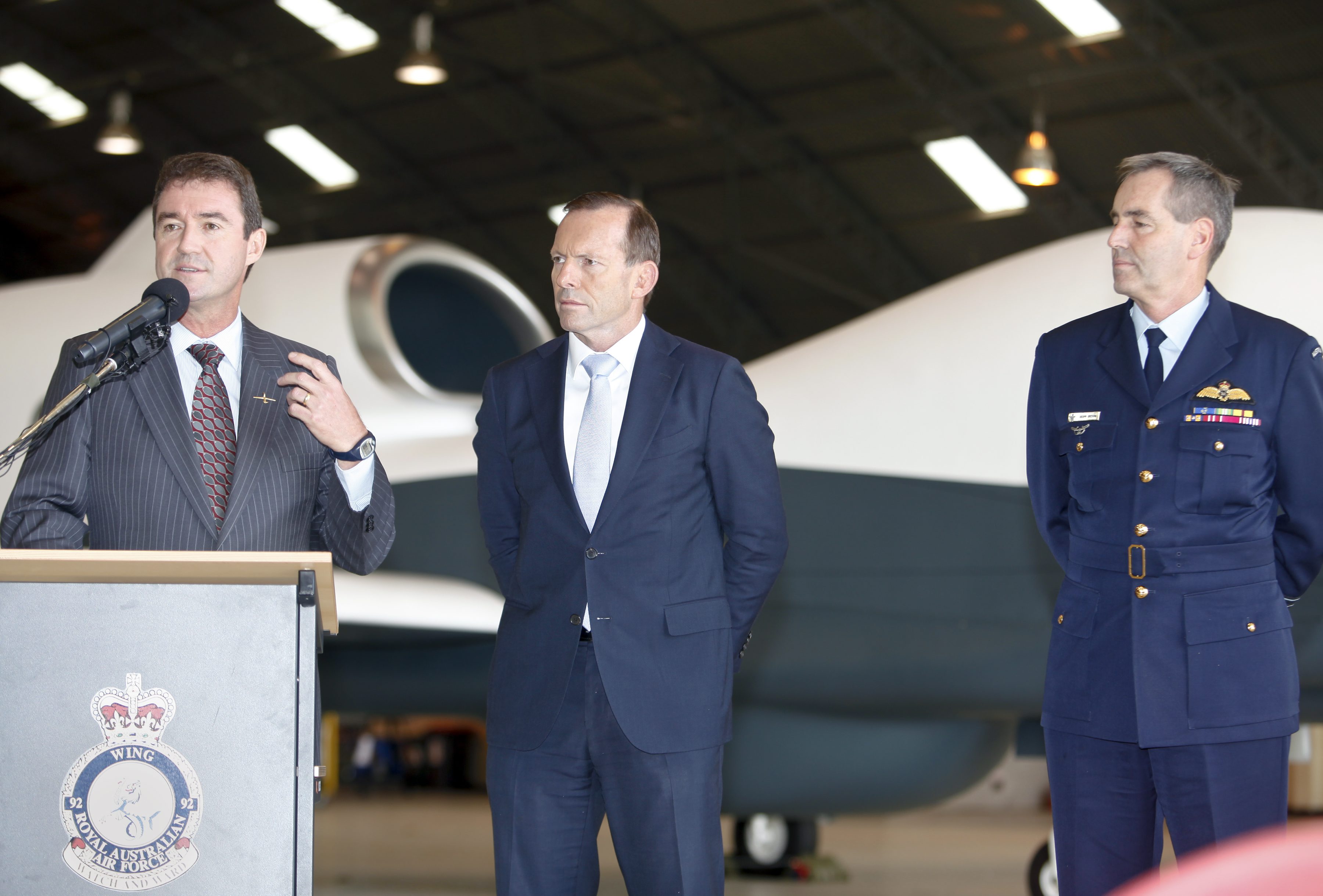 Three man stand in a row, with former prime minister Tony Abbott in centre, 