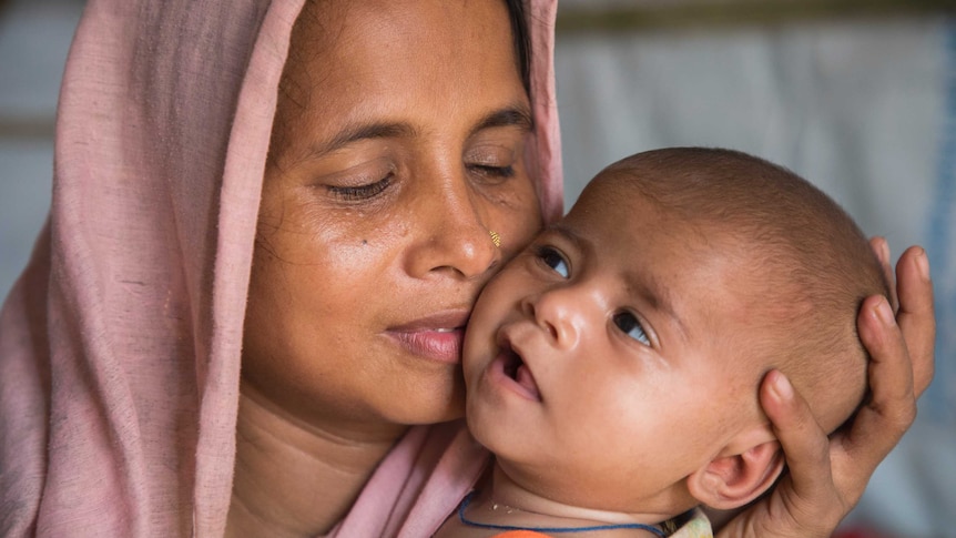 A woman from Myanmar holds her baby close to her face.