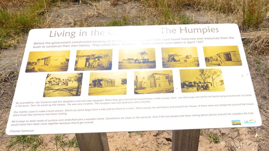 A sign in the bush featuring historical black and white photos and descriptions of life on the reserve