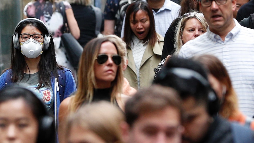 A woman wears a face mask as smoke haze is seen over Sydney.