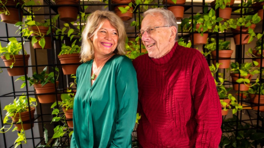 Deb Tribe and Jon Lamb standing next to each other in front of a wall covered in pot plants.
