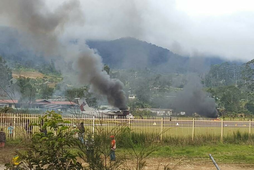 Smoke rising from a burning plane on the tarmac.