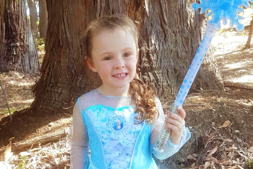 A young girl wears a blue fairy outfit and holds a wand