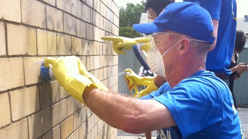 Campbell Newman cleans graffiti while campaigning.