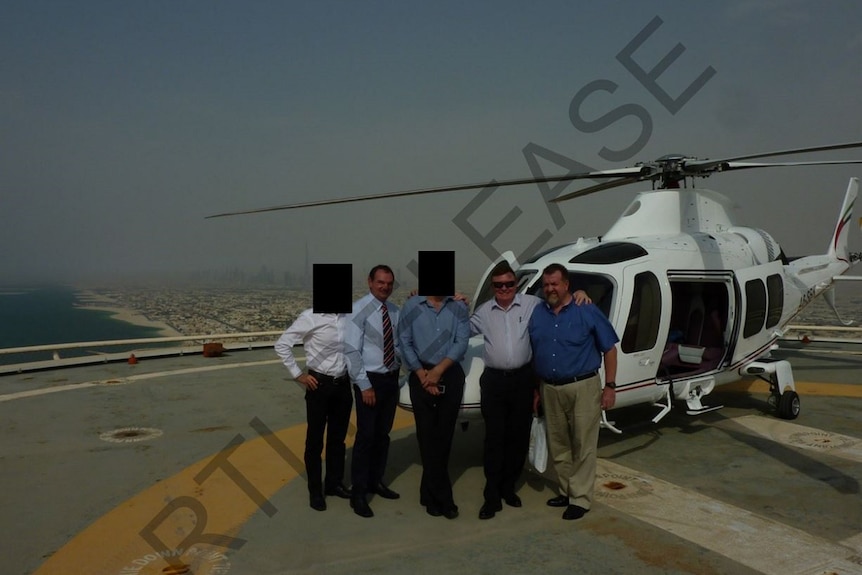 Paul Pisasale, Carl Wulff and Paul Tully with others stand next to a helicopter.
