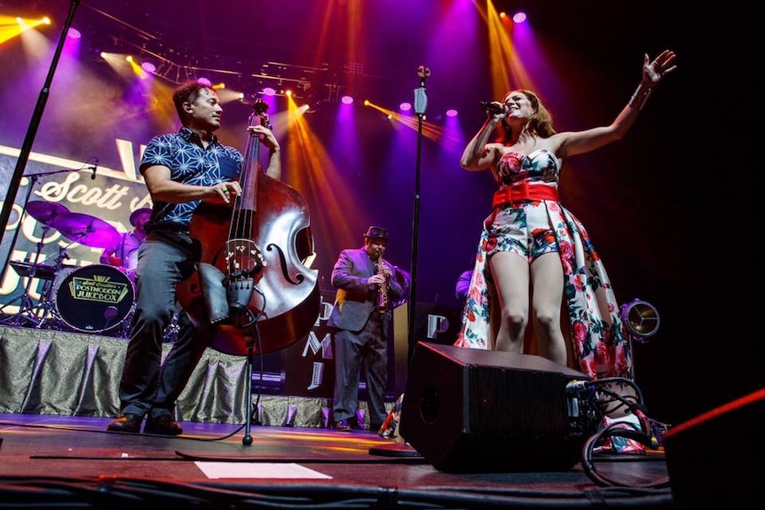 Postmodern Jukebox perform live with Adam Kubota playing while looking at their singer.