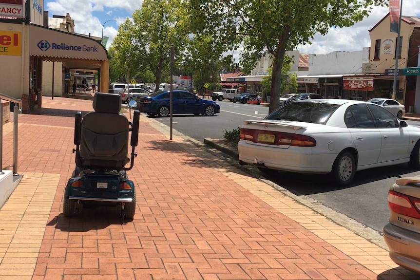 A mobility scooter in front of rear to kerb angled parked cars