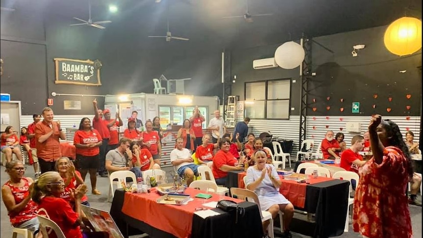 A crowd of people wearing red labor shirts celebrate in a large room.
