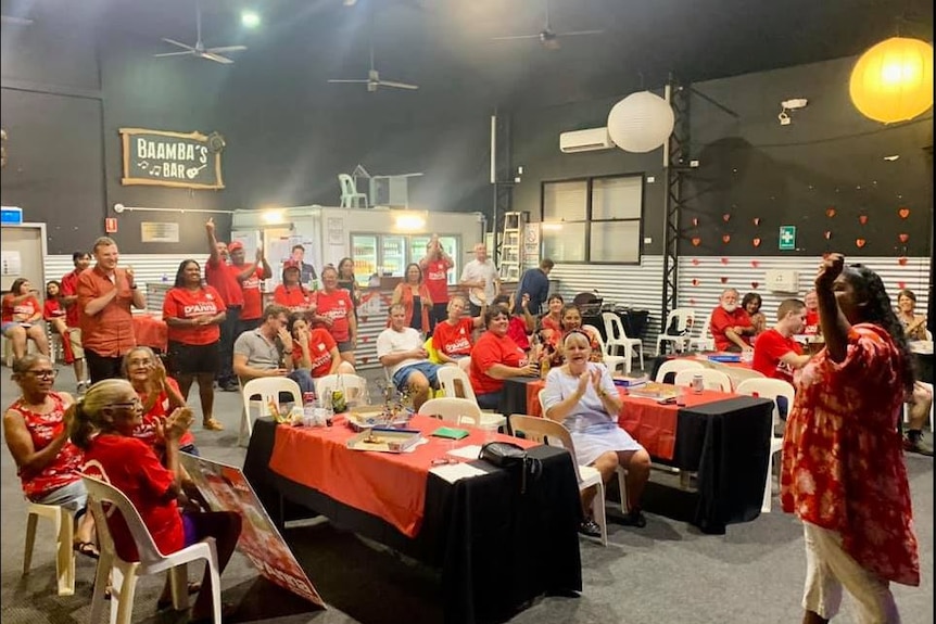 A crowd of people wearing red labor shirts celebrate in a large room.