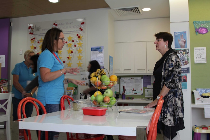 Two women speaking across a table.