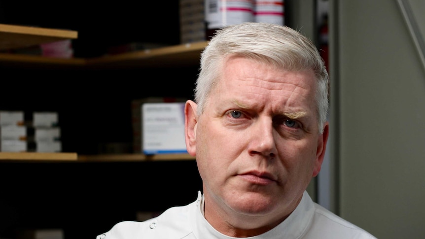 Pharmacist Iain Cartney stares down barrel of camera.