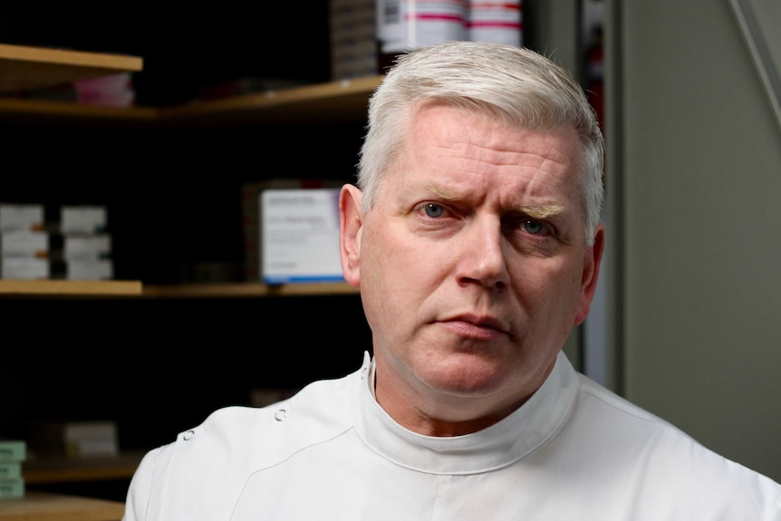 Pharmacist Iain Cartney stares down barrel of camera.