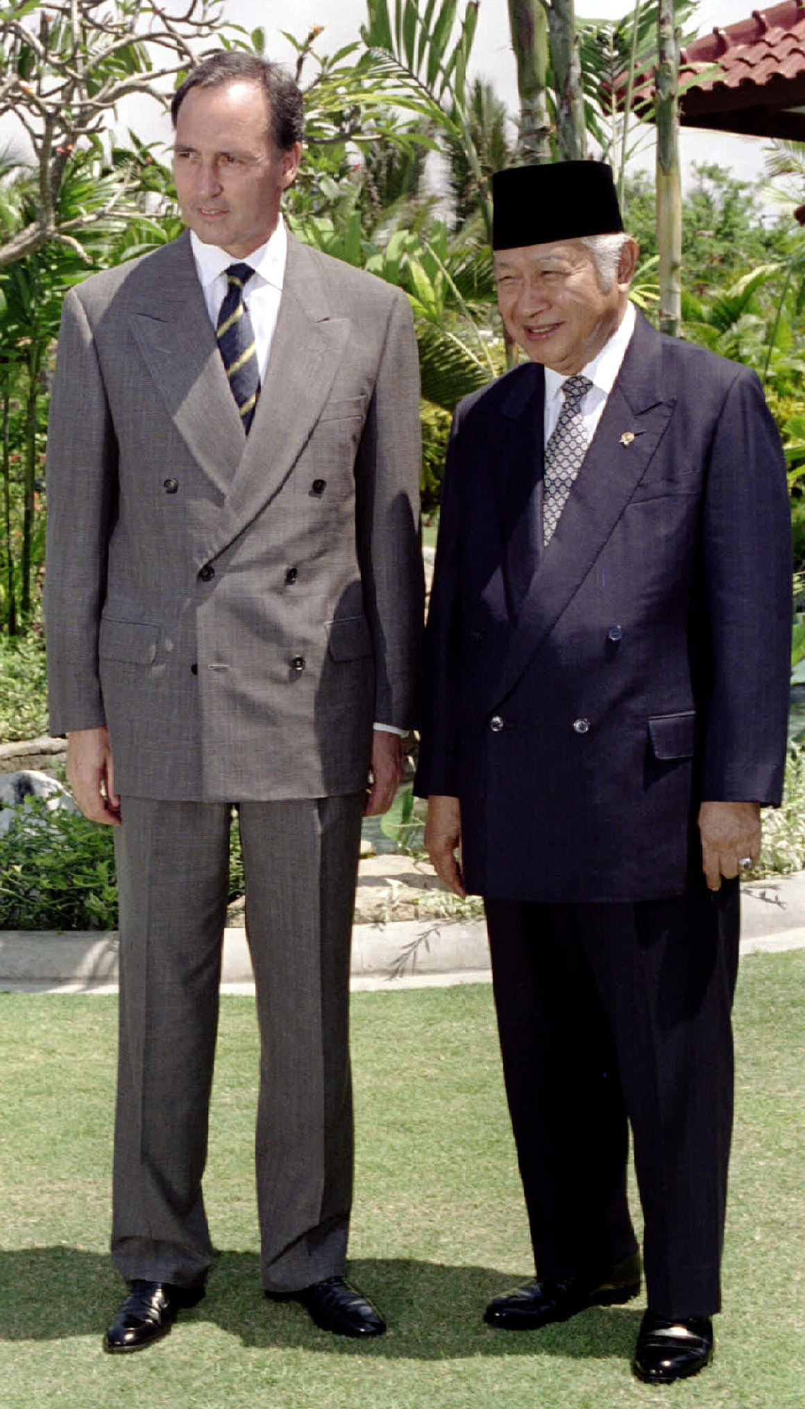 Vintage photo of a young Paul Keating in a brown suit standing next to Suharto in a dark suit and Indonesian hat.