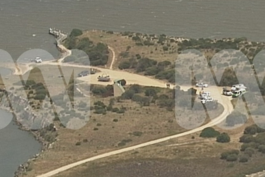 Ambulance and police vehicles parked on a sandy road