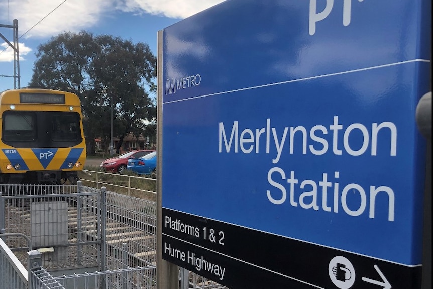 A close up of the blue and black Metro train sigh for Merlynston train station as a train approaches.