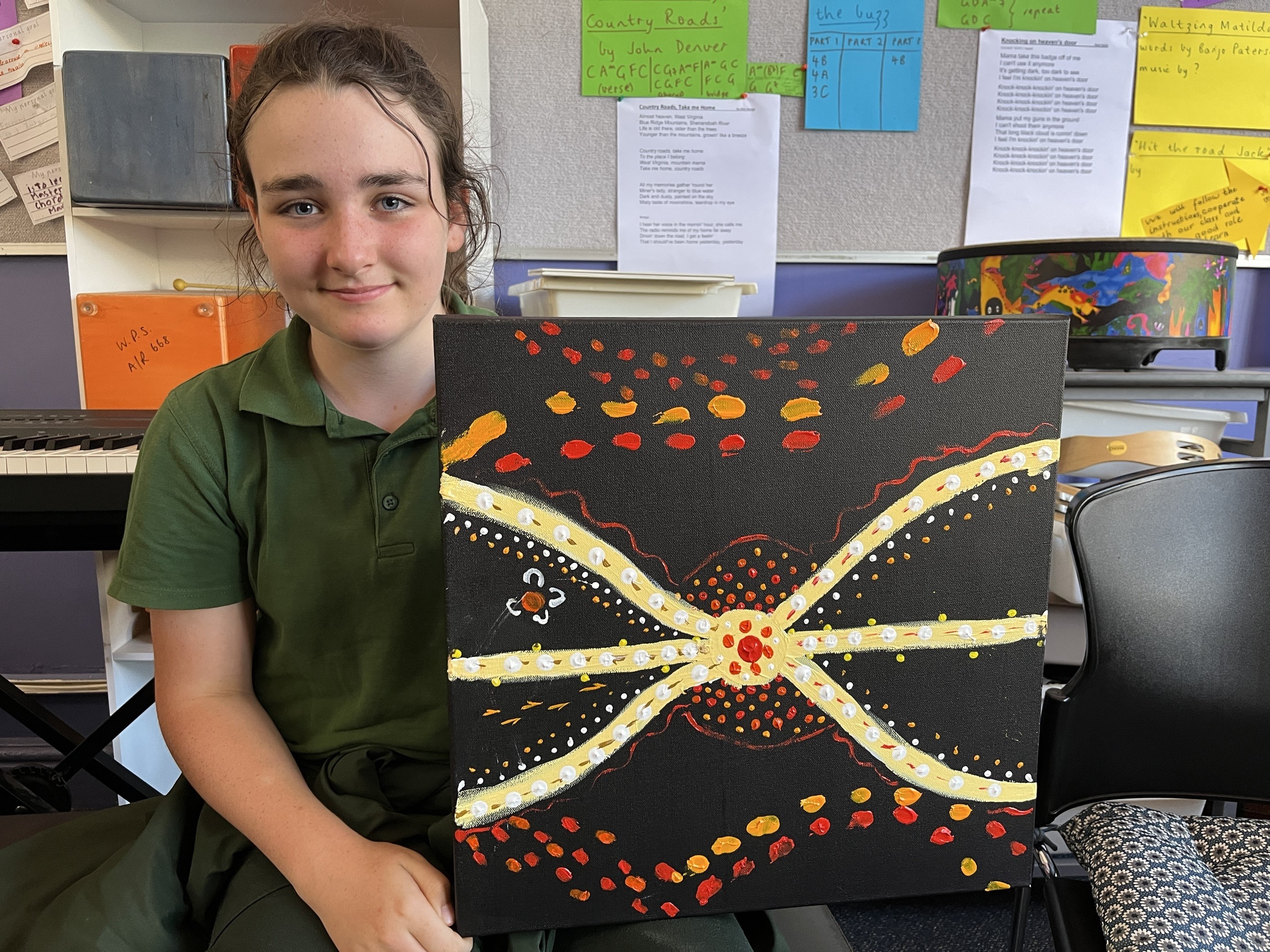 a young girl holds a painting she has done.