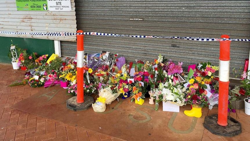 Flowers placed at the doors to the cafe in Ravenshoe torn apart by an explosion on Tuesday.