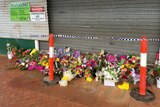 Flowers placed at the doors to the cafe in Ravenshoe torn apart by an explosion on Tuesday.