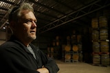 a man stands in a room full of whiskey barrels