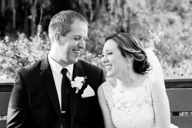 A black and white photo of a laughing bride and groom