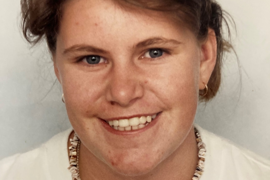 a young woman smiling into the camera in an old photo