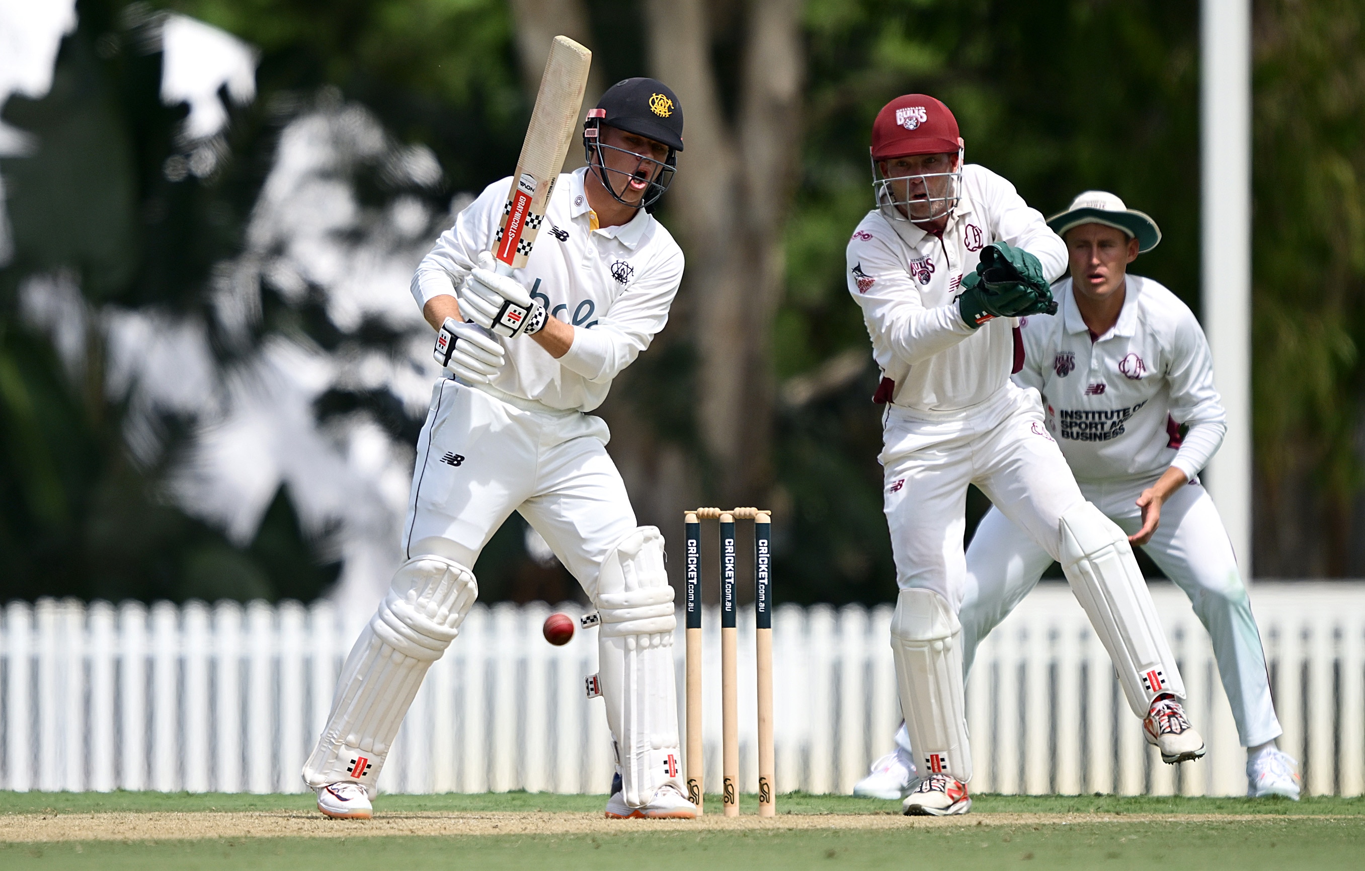 A man with a cricket bat tries to strike the ball which went through to the keeper