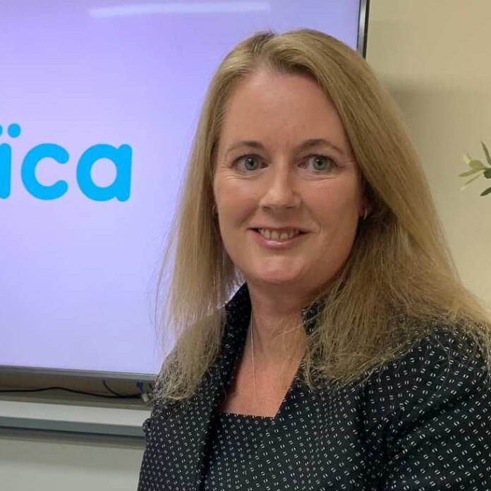 Legal Aid Family Law Practice Manager Kristen Wylie stands in front of a TV screen displaying a logo that says "amica"