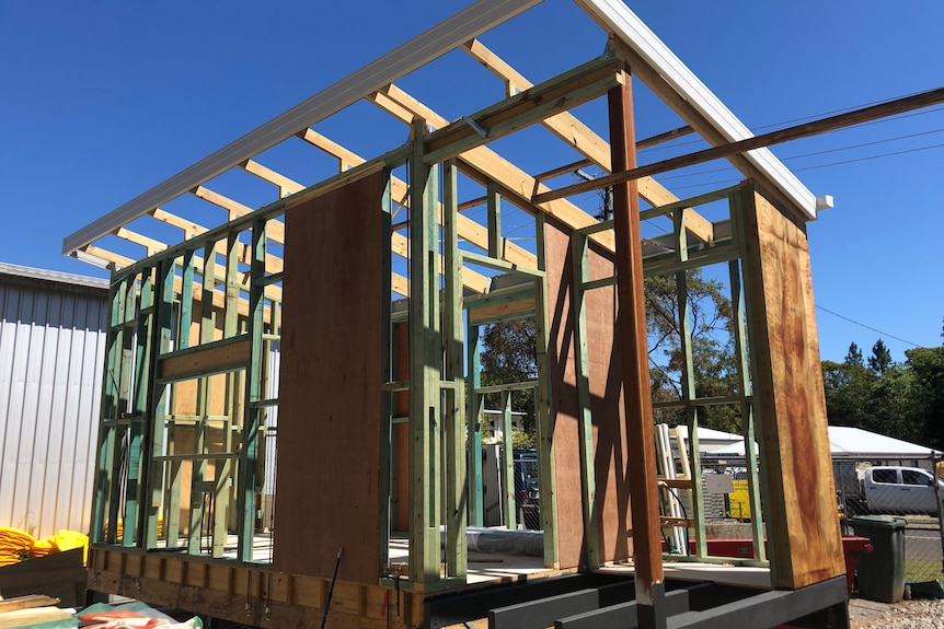 Blue and brown timber frame for a tiny home under construction against a blue sky